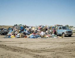 Haufen von Abfall und Sperrmüll auf einem Schotterplatz mit einem alten Lieferwagen.