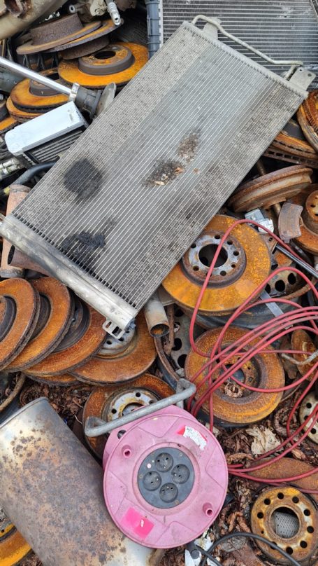 Anhäufung von alten Metallteilen, Kabeln und rotierenden Scheiben in einem Schrottplatz.