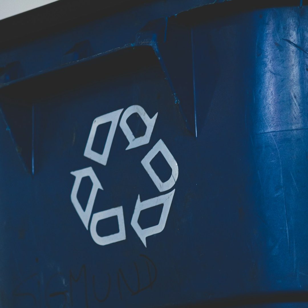 Blauer Abfallbehälter mit Recycling-Symbol.
